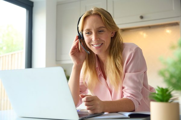 Egy hölgy angolt tanul otthonról, laptopon és fülhallgatón keresztül