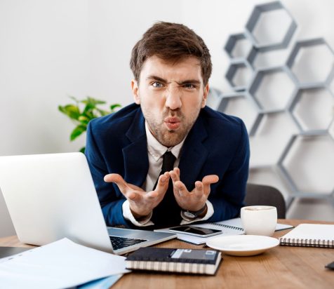 angry-young-businessman-sitting-workplace-office-background
